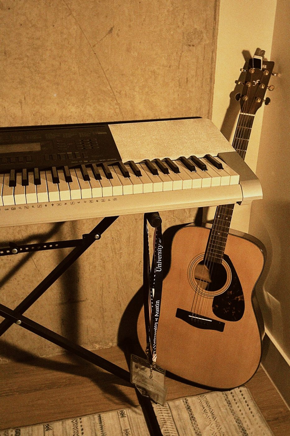 A keyboard and acoustic guitar in lamplight